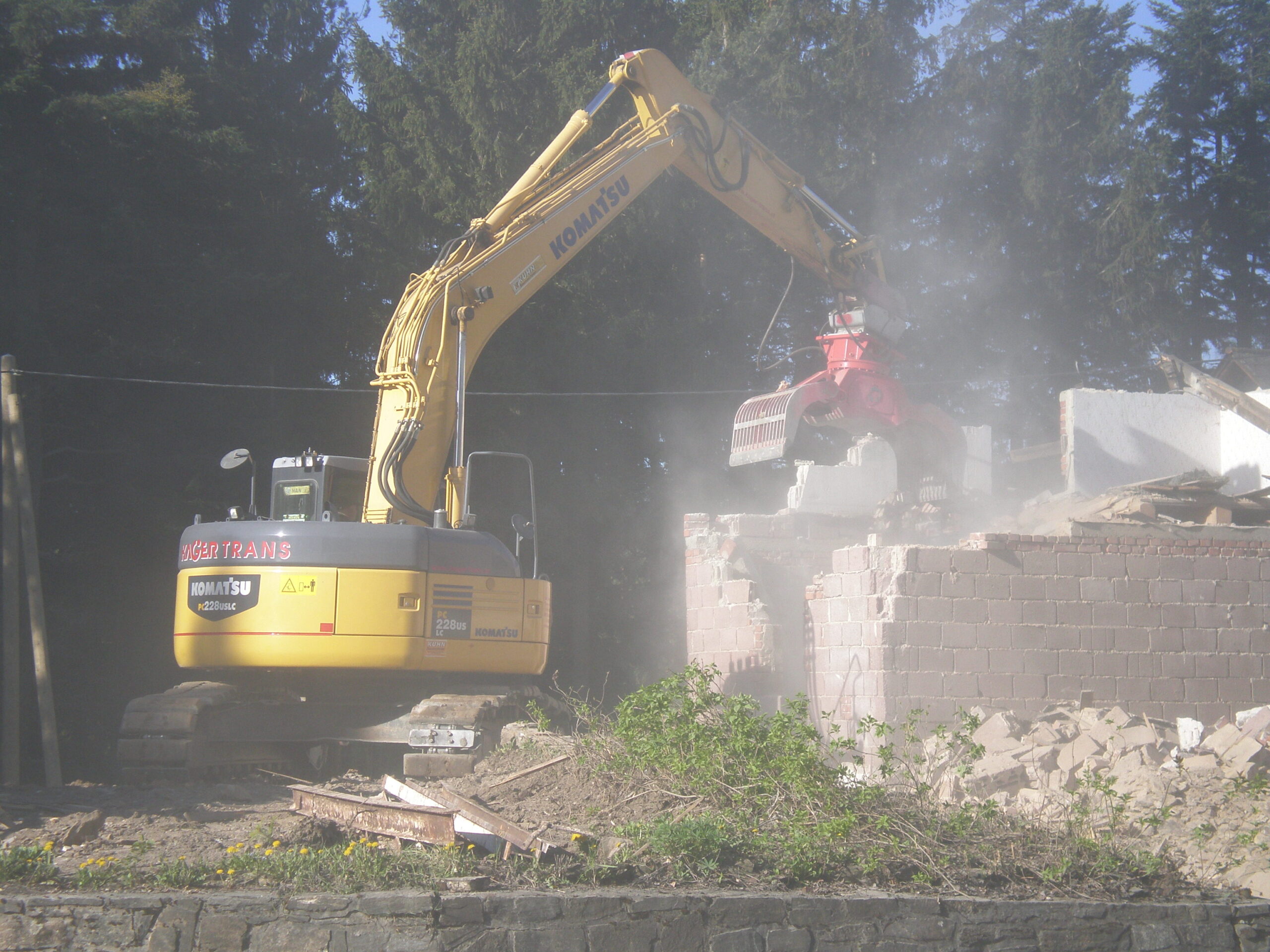 Gelber Bagger beim Abriss eines Gebäudes in bebautem Gebiet